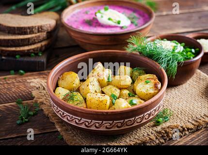 Fette di patate cotte al forno in una ciotola su un tavolo di legno. Pranzo delizioso. Foto Stock