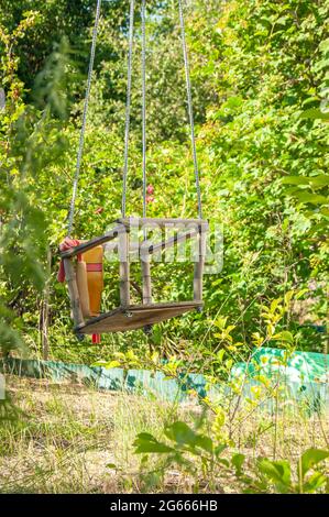 Un'oscillazione sopravfatta e abbandonata regolata nel mezzo della foresta. Un sacco di erba. La natura assume il controllo. Sensazioni strane. Foto Stock