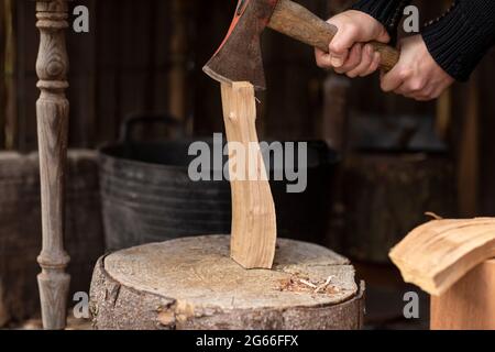 Lumberjack spaccando un ceppo di legna da ardere con una vecchia ascia su un grosso ceppo di legno da utilizzare per la sua stufa a legna, mentre è autosufficiente e vivere il Foto Stock