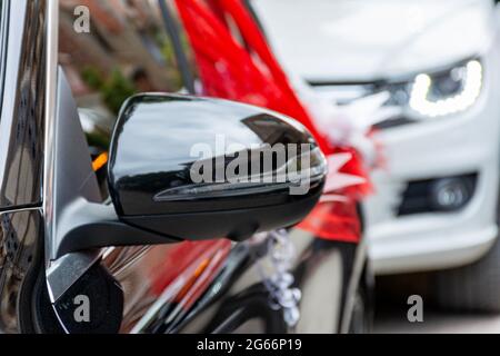 Auto da sposa nera, specchio per la visione laterale, tessuto organza rosso, arco a nastro. Foto Stock