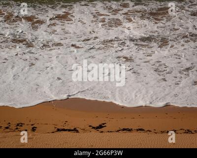 White Spume conosciuto come Sea, Ocean o Beach Foam creato dall'agitazione di acqua di mare Foto Stock