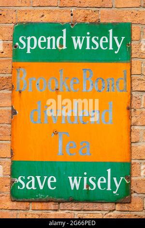 Antico segno di pubblicità Tinplate su una parete di mattoni, per Brooke Bond Dividend Tea. Spendere saggiamente, risparmiare saggiamente Foto Stock