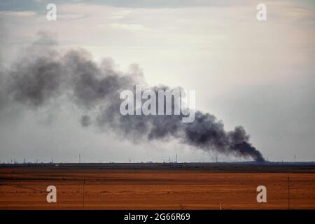 Bruciando fumo nero edificio contro il cielo, bruciando olio. Fuoco su campo agricolo. Emissione di fumo nero da Burning Building Against Sky Foto Stock