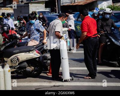 Residenti che trasportano bombole di ossigeno riempite. La domanda di bombole di ossigeno e ricariche per esigenze mediche domestiche è aumentata. Ciò è parallelo all'aumento dei casi di Covid-19 in Indonesia nelle ultime settimane. Come è accaduto in uno dei magazzini di rifornimento di ossigeno a Manggarai, nel sud di Giacarta, decine di residenti erano disposti a fare la coda per ore solo per riempire le bombole di ossigeno. Essi cercano questi articoli per fornire ossigeno per la loro famiglia che stanno subendo un trattamento indipendente a casa, perché quasi ogni singolo ospedale sono completamente caricati, ha detto uno di residenti. Tuttavia, non solo alcuni res Foto Stock