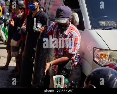 Un residente sta trasportando una bombola di ossigeno da riempire. La domanda di bombole di ossigeno e ricariche per esigenze mediche domestiche è aumentata. Ciò è parallelo all'aumento dei casi di Covid-19 in Indonesia nelle ultime settimane. Come è accaduto in uno dei magazzini di rifornimento di ossigeno a Manggarai, nel sud di Giacarta, decine di residenti erano disposti a fare la coda per ore solo per riempire le bombole di ossigeno. Essi cercano questi articoli per fornire ossigeno per la loro famiglia che stanno subendo un trattamento indipendente a casa, perché quasi ogni singolo ospedale sono completamente caricati, ha detto uno di residenti. Tuttavia, non solo alcuni resid Foto Stock