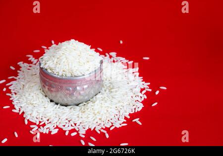 Riso di gelsomino tailandese in un contenitore d'argento su sfondo rosso. Spazio di copia. Foto Stock