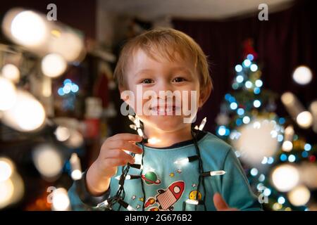 Un ragazzino a Natale che tiene le luci della fata Foto Stock