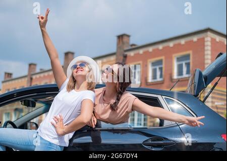 Due donne stanno ingannando intorno all'automobile. Girlfriends in auto Foto Stock