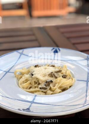 Pasta fatta in casa con tartufi di funghi in una salsa cremosa cosparsa di parmigiano Foto Stock