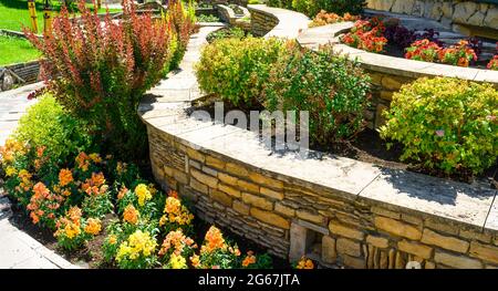 Progettazione paesaggistica di giardino casa piacevole, paesaggistica con pareti di ritegno e aiuole in cortile casa residenziale. Splendido paesaggio all'aperto Foto Stock