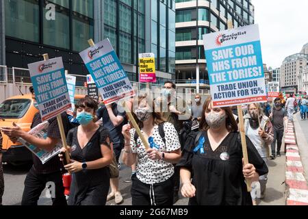 Manifestanti che tengono cartelli che dicono 'salvare la nostra NHS dalle torie! Azione sindacale per il 15% nel corso del mese di marzo. Durante la pandemia, l'NHS ha sperimentato un personale insufficiente. Gli operatori sanitari hanno lavorato per lunghe ore e sono stati sottoposti a stress in relazione alla cura di grandi volumi di casi COVID 19. Organizzato da Unite the Union, una marcia che cerca di rimproverare l’aumento salariale dell’1% proposto dal governo Boris Johnson, e chiede un aumento salariale del 15% si è svolto dall’University College Hospital attraverso Trafalgar Square e si è chiuso fuori Downing Street. Foto Stock