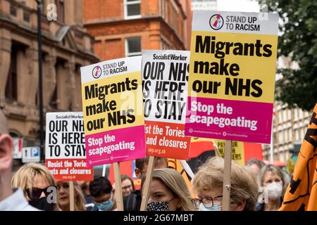 Durante il mese di marzo i manifestanti hanno appostato cartelli che dicono "i migranti fanno il nostro NHS" e "il nostro NHS è qui per rimanere". Durante la pandemia, il NHS ha sperimentato un personale insufficiente. Gli operatori sanitari hanno lavorato per lunghe ore e sono stati sottoposti a stress in relazione alla cura di grandi volumi di casi COVID 19. Organizzato da Unite the Union, una marcia che cerca di rimproverare l’aumento salariale dell’1% proposto dal governo Boris Johnson, e chiede un aumento salariale del 15% si è svolto dall’University College Hospital attraverso Trafalgar Square e si è chiuso fuori Downing Street. Foto Stock