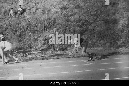 1960s, storico, atletica, sport scolastici, fuori su una pista da cenere, un giovane atleta maschile in posizione, in procinto di iniziare una gara sprint, in gara in una giornata sportiva intercontea, Inghilterra, Regno Unito. Foto Stock