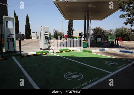 Due stazioni di ricarica per auto elettriche con posti auto verdi designati contrassegnati in ebraico per auto elettriche solo presso una stazione di benzina o un distributore di benzina regolare. Foto Stock