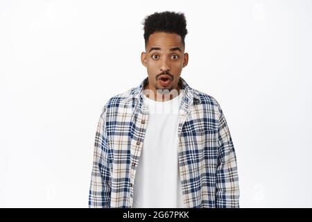 Stupito e impressionato l'uomo afroamericano, il gasp e la stare stupito alla macchina fotografica. Ragazzo nero in awe guardando smth impressionante, controllando le vendite speciali Foto Stock