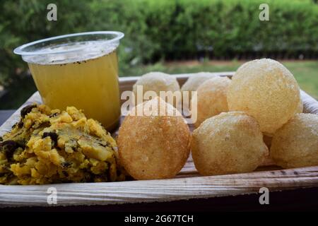 Gustosi spuntini indiani Pani puri con acqua di masala chat e cipolle affettate. Piatto tradizionale indiano snack noto anche come palline d'acqua, Golgappe, puchka. Foto Stock