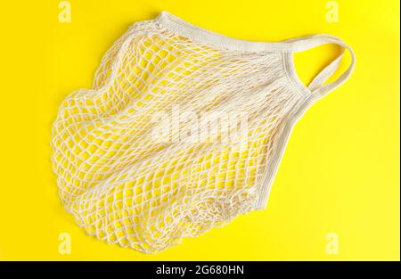 Borsa in mesh ecologica su sfondo giallo. Sacchetto di cotone biologico riciclabile. Stile di vita sostenibile e shopping. Foto Stock