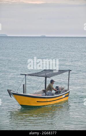 Terengganu, Malesia: 13 settembre 2014 - un pescatore sulla sua piccola barca che esce al mare. Punti di messa a fuoco selettivi. Sfondo sfocato Foto Stock