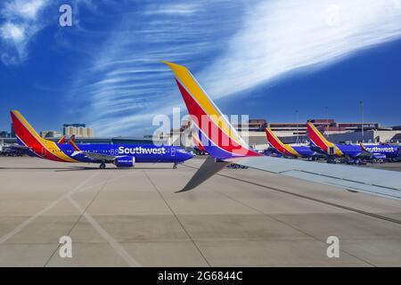 Una formazione di aerei Southwest Airlines alle porte del terminal presso l'aeroporto internazionale McCarran di Las Vegas, Nevada, con casinò in lontananza Foto Stock