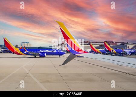 Una formazione di aerei Southwest Airlines alle porte del terminal presso l'aeroporto internazionale McCarran di Las Vegas, Nevada, con casinò in lontananza Foto Stock