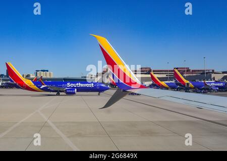 Una formazione di aerei Southwest Airlines alle porte del terminal presso l'aeroporto internazionale McCarran di Las Vegas, Nevada, con casinò in lontananza Foto Stock