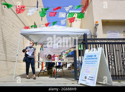 Sito di vaccinazione Covid-19 sul marciapiede allestito con tenda e lavoratori che offrono vaccini Pfizer con decorazione di bandiere di carta in Little Italy, San Diego Foto Stock