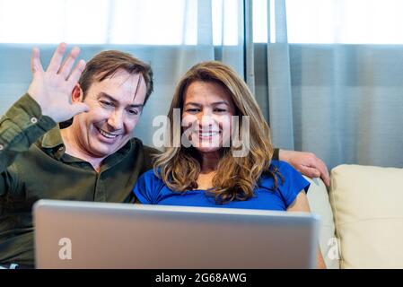 Uomo e donna sorridenti e maturi che parlano in videochiamata con il computer portatile Foto Stock