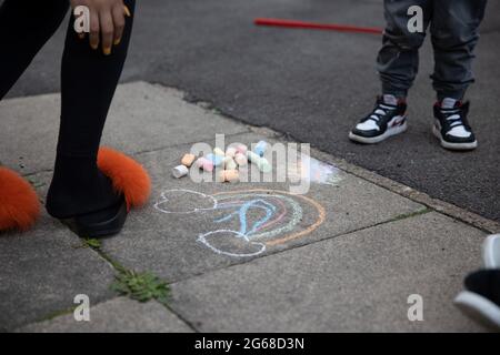 I giovani residenti si tirano sul pavimento prima dell'inizio della partita.UN tifoso di calcio, Chris Ralph Dowes, ha organizzato la decorazione di oltre 400 bandiere di St George mostrate nella Kirby Estate nel sud-est di Londra insieme ad altri residenti prima dell'inizio del torneo di UEFA Euro 2020. La tradizione della tenuta di mettere in su centinaia delle bandiere di San Giorgio è stata dal 2012 Euro ed ogni volta i residenti sono riusciti ad inserire più bandiere nella tenuta. Durante ogni partita del team inglese, Chris sarà l'ospite e inviterà gli altri residenti a unirsi a guardare. Ha detto che tutte le bandiere sarebbero restate fino a. Foto Stock