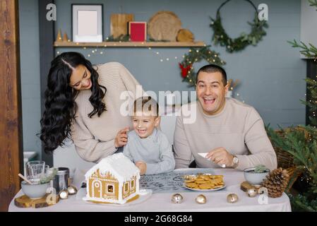 Una famiglia felice di stile decora una casa di pan di zenzero Foto Stock