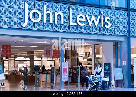 Gli acquirenti escono dal grande magazzino John Lewis presso il centro commerciale Westfield di Londra, Inghilterra, Regno Unito durante gli sconti estivi Foto Stock