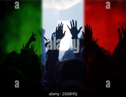 Tifosi di calcio che sostengono l'Italia - folla che festeggia nello stadio con mani alzate contro la bandiera italiana Foto Stock