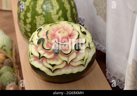 Intagliando un bel fiore intagliato su un grande cocomero maturo in onore della festa della vendemmia autunnale Foto Stock