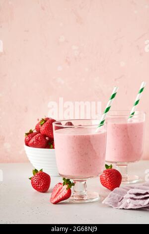 Due frullato di fragola o frullato con frutti di bosco e menta in vetro su sfondo rosa chiaro. Frullato estivo, frullato di latte e rinfresco biologico co Foto Stock