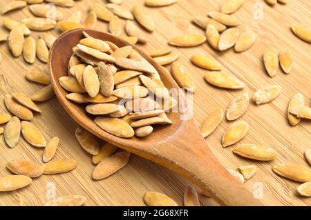 Semi di melone secchi organici salati arrosto, su tagliere di bambù in cucchiaio di legno Foto Stock