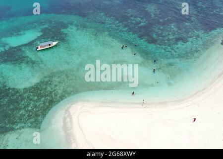 Vista dall'alto del drone aereo delle persone che praticavano snorkeling sulla barriera corallina, con acque cristalline dell'oceano in barca e passeggiata sulla spiaggia di sabbia bianca. Isola di Tinggi o Pulau Foto Stock