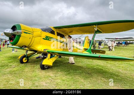 Un uomo in uniforme militare ispeziona un 1937 Beechcraft 17S Staggerwing, NC 18028, a Middle Wallop, Hampshire, Regno Unito Foto Stock