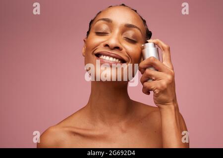 Ritratto closeup di una donna con pelle sana usando siero sul viso. Bella donna che applica l'olio essenziale al suo viso. Foto Stock