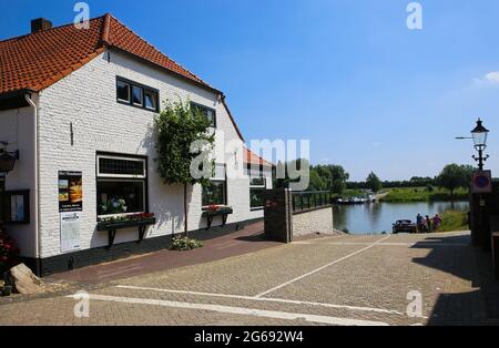 Broekhuizen, Paesi Bassi - 1 luglio. 2021: Vista sul vecchio hotel turistico rurale sul fiume maas vicino al molo dei traghetti nel piccolo villaggio olandese in estate Foto Stock