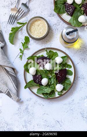 Insalata sana con rucola, spinaci, barbabietole, mozzarella e vinaigrette su un piano in pietra grigia. Vista dall'alto sfondo piatto. Copia s Foto Stock