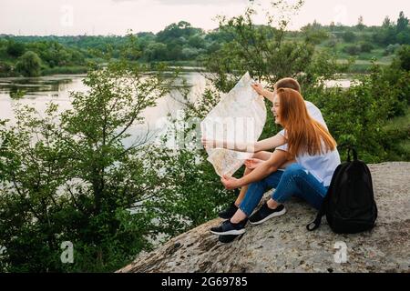 I viaggiatori soli, la pianificazione delle vacanze locali, le vacanze in luoghi visitano coppia. Coppia in amore turista seduto sulla pietra vicino al fiume leggere la mappa Foto Stock