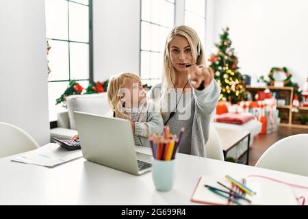 Madre di figlia caucasica che indossa cuffie per agente del call center a casa puntando con le dita verso la fotocamera e verso di te, gesture sicuro guardando seriou Foto Stock