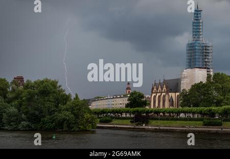 04 luglio 2021, Hessen, Francoforte sul meno: Lampi attraverso il cielo sul sud-est della città, che è oscurato dalle nuvole di pioggia. Sulla destra si trova la torre a ponteggio della Dreikönigskirche. Il Servizio meteorologico tedesco (DWD) aveva messo in guardia da forti tempeste in alcune parti dell'Assia. Foto: Frank Rumpenhorst/dpa Foto Stock