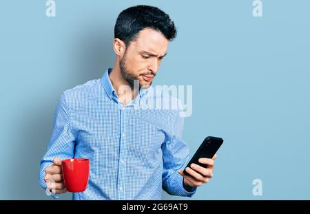 Uomo ispanico con barba usando smartphone e bevendo una tazza di caffè scettico e nervoso, rondante sconvolto a causa del problema. Persona negativa. Foto Stock