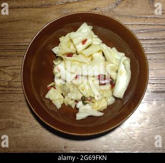 cavolo salato con pepe rosso nel recipiente marrone sul tavolo di legno Foto Stock