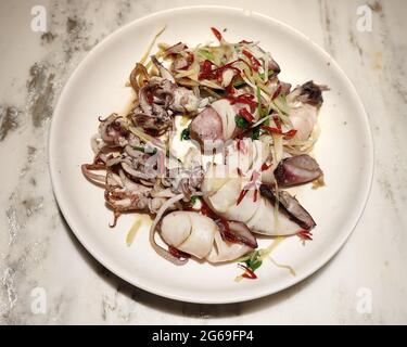 calamari brasati freschi con pepe rosso nel piatto bianco pronto per essere mangiato Foto Stock