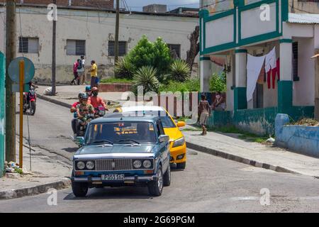 Auto russa Lada girando su un angolo a Santiago de Cuba, Cuba. Le persone occasionali indossano maschere facciali di protezione Foto Stock