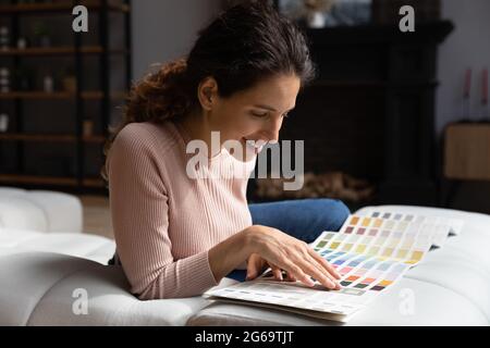 Felice giovane signora che pianifica il rinnovo degli appartamenti usando la tavolozza dei colori. Foto Stock
