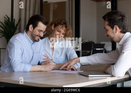 Felice giovane coppia firma il contratto all'incontro con la mangiatoia Foto Stock