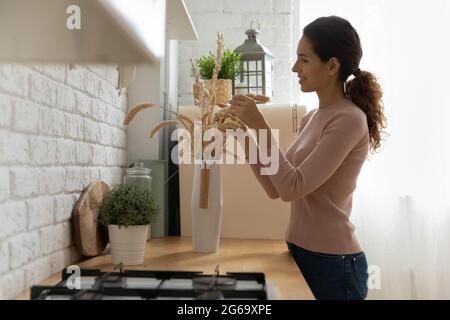 Sorridente padrona di casa migliorando la dimora con fiori secchi. Foto Stock
