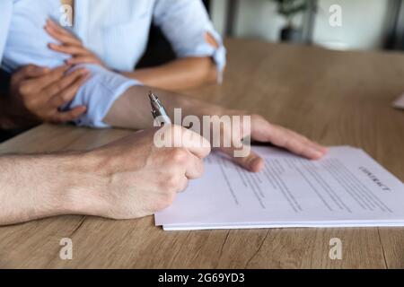 Primo piano di giovane coppia firma contratto alla riunione Foto Stock